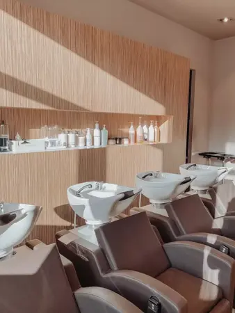 Moderne Friseur Waschstation mit bequemen Stühlen und Haarpflegeprodukten im Salon.