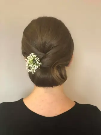 Elegante Hochsteckfrisur mit glattem Haar und weißem Blumenschmuck im Nacken.